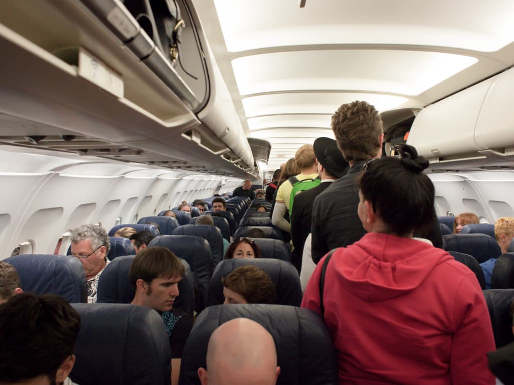 People waiting in the middle of an airplane.